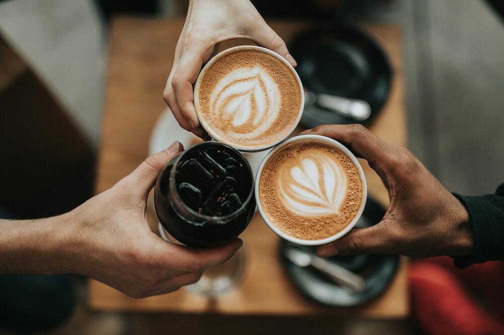 Two lattes with latte art being clinked together