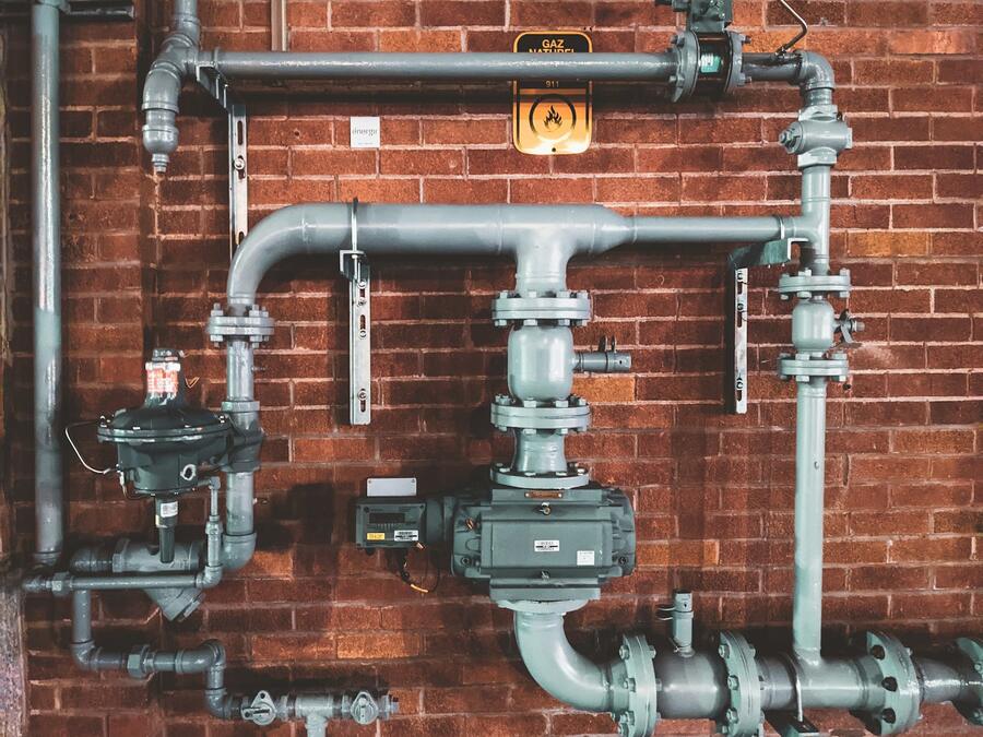 Copper and steel pipes with valves on a brick wall
